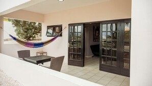 A covered patio with a hammock, a dining table, chairs, and a door leading to an interior space. - Studio Bientu- centrally located-near trendy beaches (Sint Michiel)