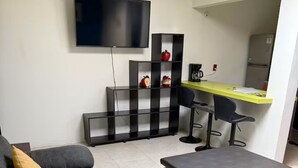 A modern living room with a sofa, ottoman, and a flat-screen TV mounted on the wall. - Downtown Apt / Walk to Main Square / Families & Groups (Zacatlán)