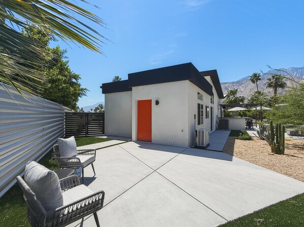 Una casa moderna con un patio, mobiliario exterior y vistas a la montaña.