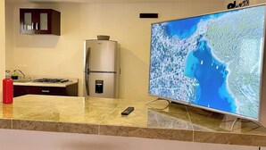 A kitchen with a large TV, two bar stools, a refrigerator, and a cabinet. - Spacious Downtown Apartment / Family Friendly + Parking (Zacatlán)
