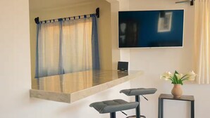 A modern kitchen with a built-in counter, a flat-screen TV mounted on the wall, and a small table with a vase of flowers. - Spacious Downtown Apartment / Family Friendly + Parking (Zacatlán)
