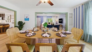 A dining area with a round table set for six, surrounded by wicker chairs, a ceiling fan, and a view into the living room. - Suncourt Retreat | Sports Court | Pool | Hot Tub (Bradenton)