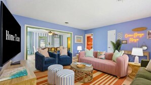 A living room with a television, sofas, ottomans, and a striped rug. - Suncourt Retreat | Sports Court | Pool | Hot Tub (Bradenton)