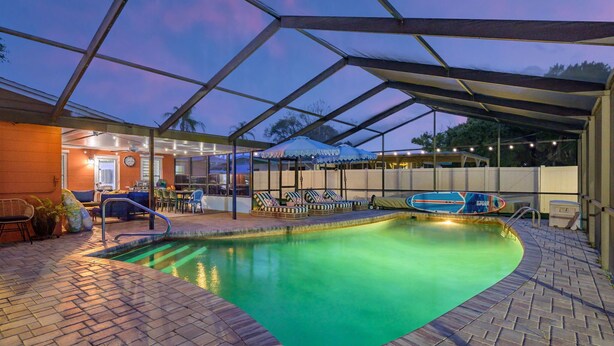 An indoor swimming pool with a glass ceiling, lounge chairs, and a poolside bar area. - Suncourt Retreat | Sports Court | Pool | Hot Tub (Bradenton)