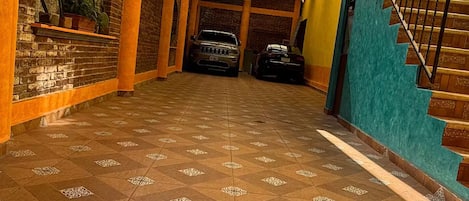 Un pasillo cubierto con baldosas estampadas, un muro de ladrillo con una planta y una escalera.