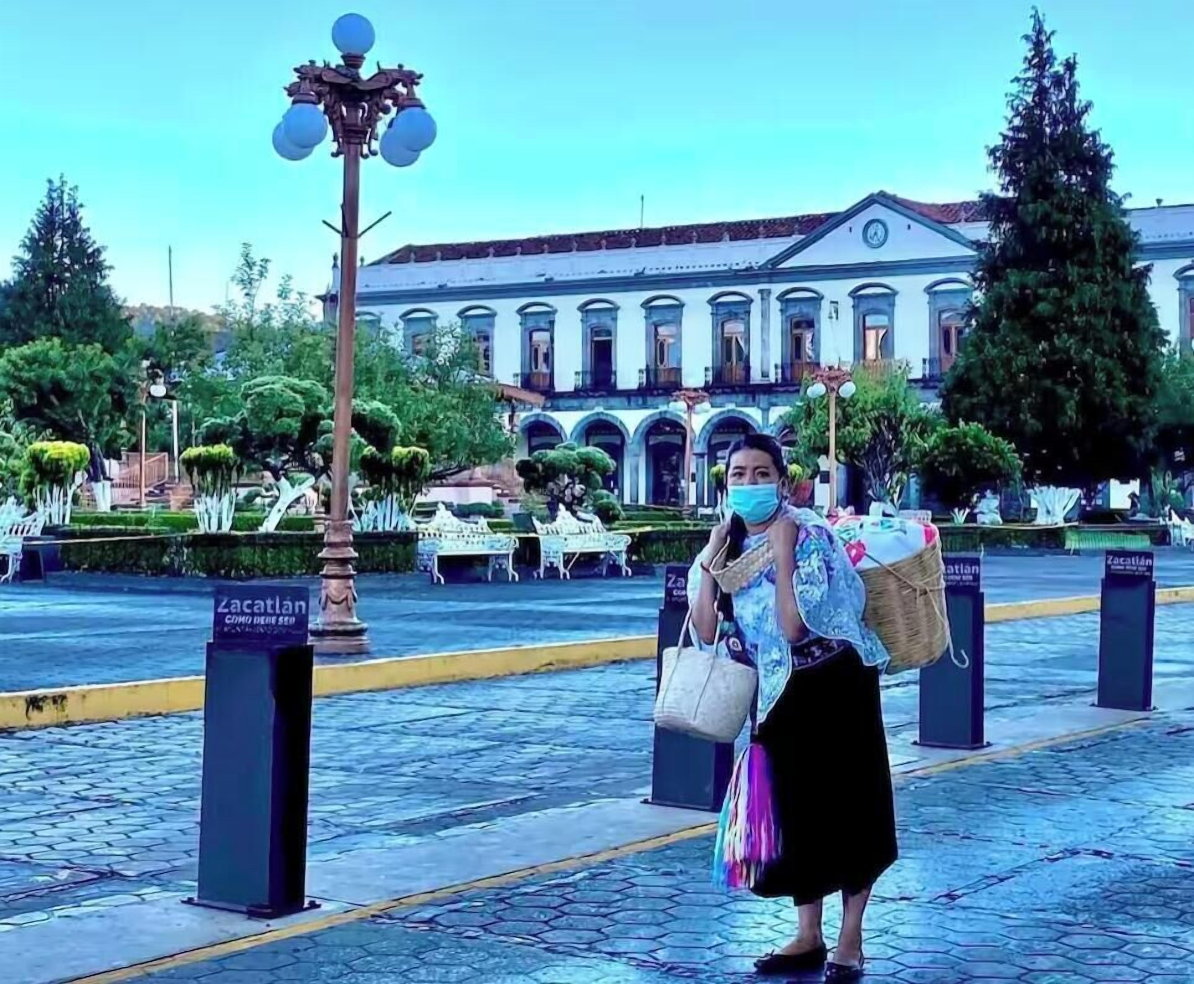 Una persona está de pie en una superficie pavimentada, con un edificio al fondo.
