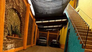 A covered walkway with patterned tiles, a brick wall with a plant, and a staircase. - Quiet Family Apartment 2 Blocks from Zacatlán Downtown (Zacatlán)