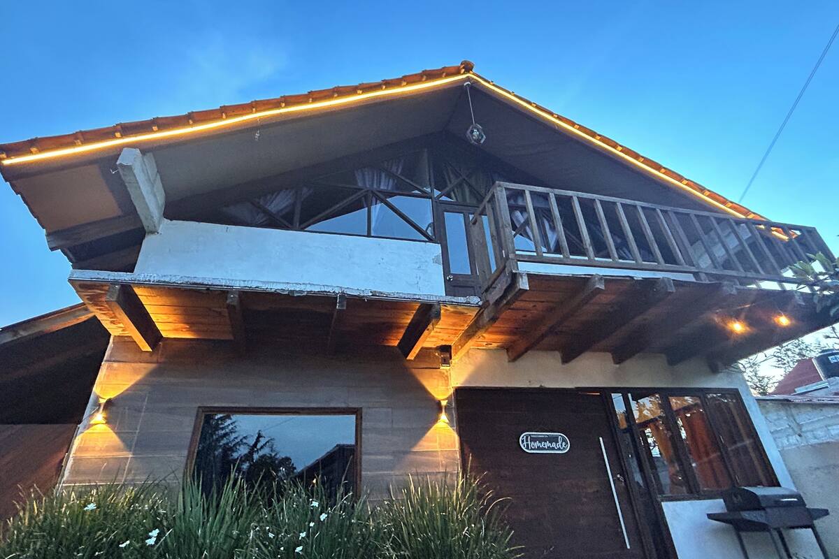 Een tweelaags gebouw met een balkon, een houten terras en een bordje met de tekst 'Homemade'.