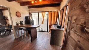 Cocina moderna con encimera de madera, taburetes de bar y vistas a través de una puerta de cristal.