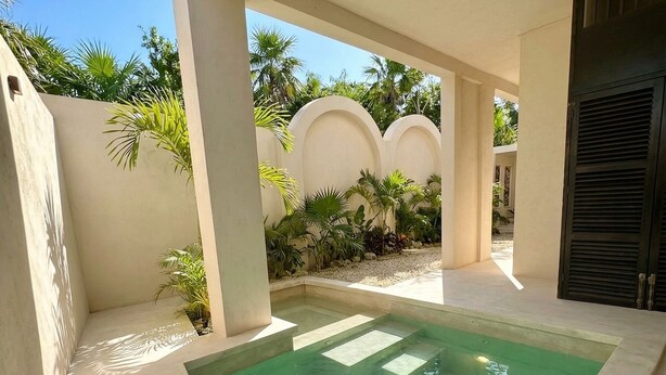 A swimming pool with clear water, surrounded by a covered area with palm trees and a view of the sky. - Jungle Villa + Private Studio w/ Rooftop Access | 2BR + Studio | Sleeps 6 (Tulum)
