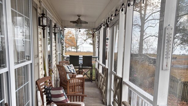 A covered porch with wooden chairs and a bench, a ceiling fan, and a view of the outdoors. - 2 bedroom and Den with a Pullout Double (Colonial Beach)