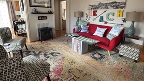A living room with a red sofa, patterned armchairs, a coffee table, a ceiling fan, and a large rug. - 2 bedroom and Den with a Pullout Double (Colonial Beach)