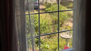 A window with a view of a garden, a hammock, and a bird feeder. - 2 bedroom and Den with a Pullout Double (Colonial Beach)