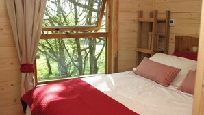 A wooden room with a bed, a window, and a ladder. - Beautiful handbuilt Treehouse sleeps 2-6 (Wootton Bridge)
