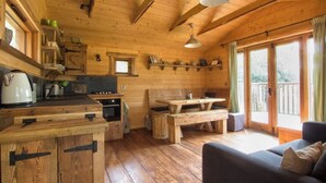 Ein Holzblockhaus-Interieur mit Küche, Essbereich und einer Couch.
