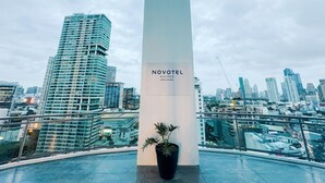 A modern hotel with a prominent column labeled 'NOVOTEL SUITES' and a view of a cityscape with high-rise buildings. - Cozy Retreat King Suite (Mandaluyong City)
