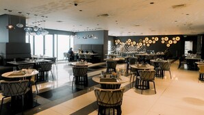 A modern restaurant with round tables and chairs, a patterned ceiling, and a wall of circular decorations. - Cozy Retreat King Suite (Mandaluyong City)