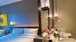 A hotel room with a bed, a large mirror, a sink, and a small potted plant. - Cozy Retreat King Suite (Mandaluyong City)