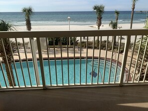 Piscina com vista para a praia e oceano, área de deck cercada e posto de salva-vidas.