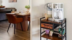 Moderni keittiö, jossa on kahvinkeitin, ruokailutila tuoleineen ja koristeellinen kattokruunu.