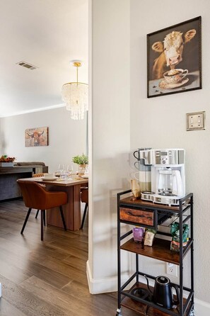 Eine moderne Küche mit Kaffeemaschine, einem Essbereich mit Stühlen und einer Kronleuchter.
