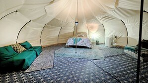 Ein Zelt mit Bett, Kissen, einem Tisch und einer Fußmatte.