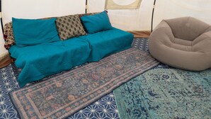 Ein Zimmer mit einer Couch, einem Sitzsack und Teppichen mit Muster.
