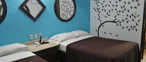 Una habitación de hotel con dos camas, un escritorio con teléfono y una pared con un mural de un árbol.