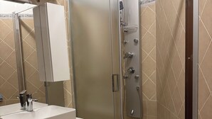 A modern bathroom with a glass-enclosed shower, a sink with a mirror, and a toilet.