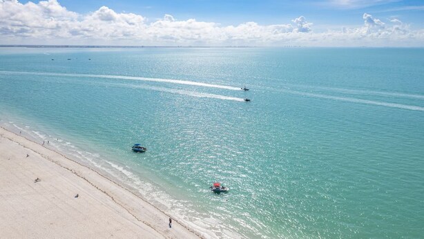 A beach with clear turquoise water, a sandy shore, and a few boats. - 2BR Retreat at Sanibel Beach Club 2 with Hot Tub (Sanibel)