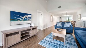 Un salon avec un meuble de rangement en bois pour les appareils multimédias, un canapé bleu et une table basse.