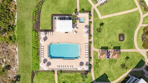 Vue aérienne d’un complexe hôtelier doté d’une piscine, de chaises longues et d’un petit espace piscine.