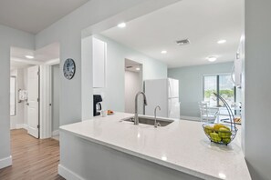 A modern kitchen with a white countertop, stainless steel sink, and a fruit bowl. - Sanibel Beach Club 2 Beachfront 2BR Escape (Sanibel)