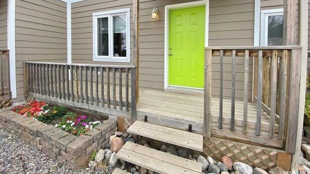 A house with a green door, a wooden porch with a railing, and a window. - Tranquil Candle Lake Townhouse Backing the 5th Green (Candle Lake)