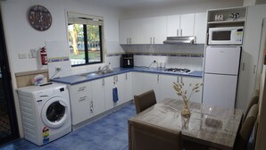Una cocina compacta con lavadora, una mesa de comedor con sillas, microondas y refrigerador.