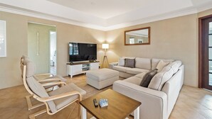 Ein modernes Wohnzimmer mit Sofa, Sessel, Hocker und Couchtisch.