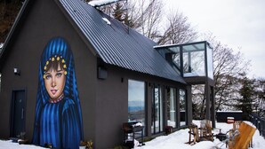 Een modern gebouw met een grote muurschildering, een glazen conservatorium en terrasjes.
