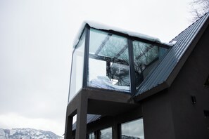 Un bâtiment moderne doté d’un balcon en verre et d’un toit en métal.