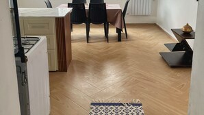 A modern kitchen with a dining area, a large window, and a patterned rug.