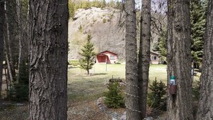 Metsäinen alue, jossa on punainen mökki ja taustalla pieni talo.
