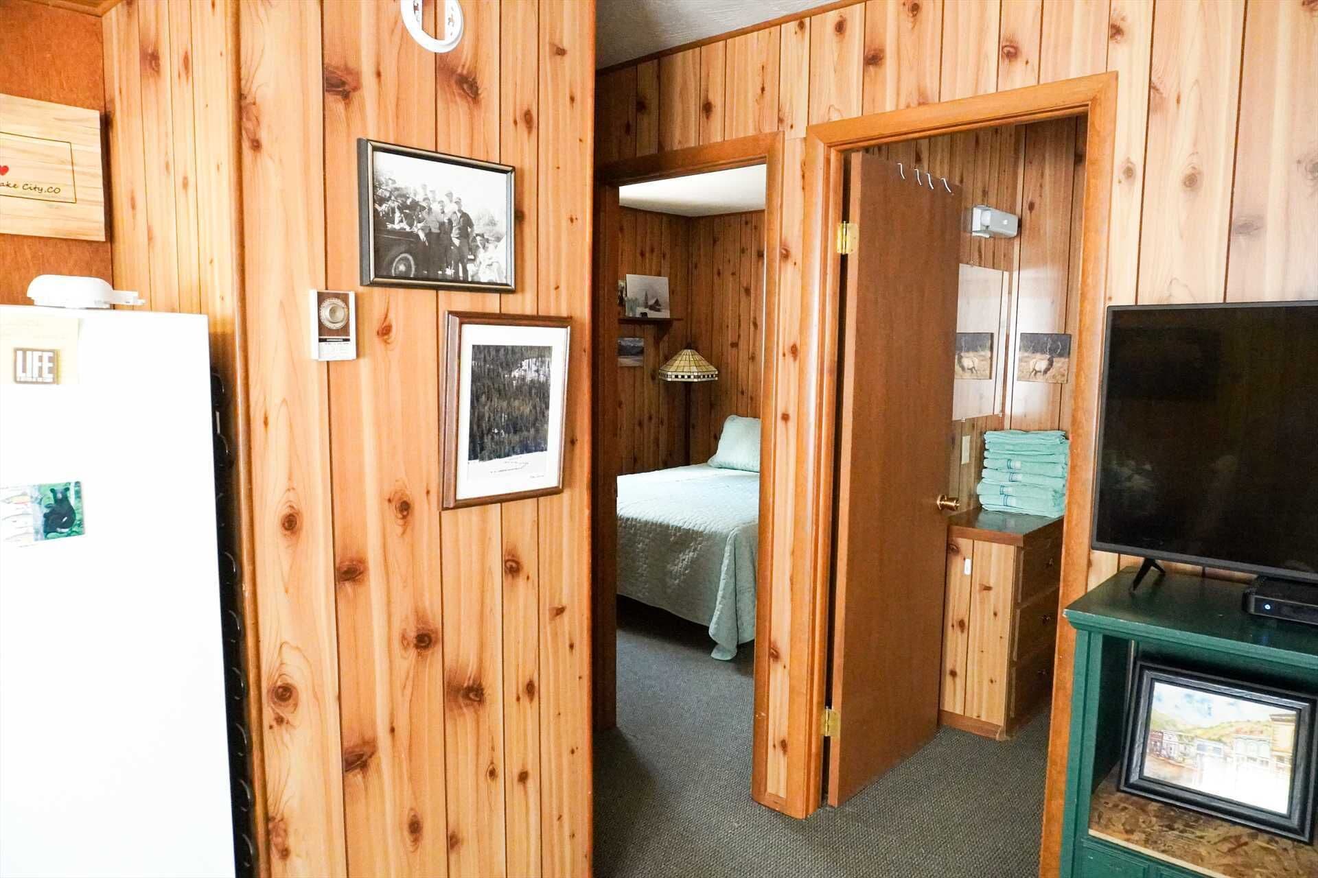 Ein Zimmer mit Holzwandverkleidung, einem Bett, einem Fernseher und gerahmten Bildern an den Wänden.