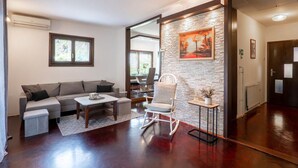 Una sala de estar con un sofá, un sillón mecededor, una mesa de centro y un comedor con una mesa y sillas.