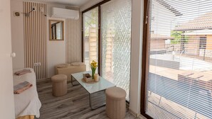 Un baño moderno con suelo de madera, una mesita con un florero y un banco.