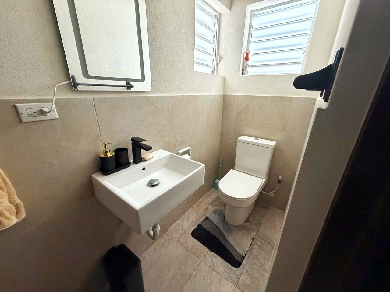 A small bathroom with a white sink, toilet, and a mirror above the sink.