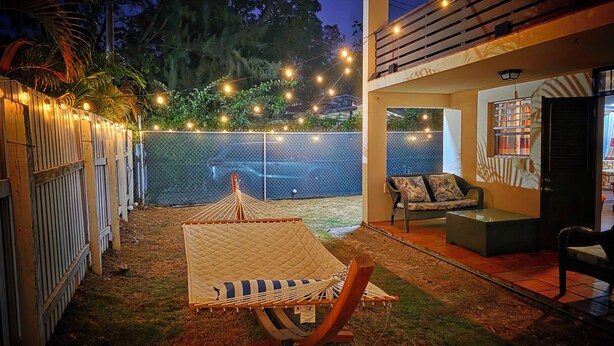 Un giardino retrostante con un'amaca, un'area salotto e luci decorative appese.