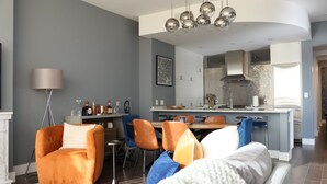 A modern living room with a sofa, chairs, a coffee table, and a dining area with a kitchen in the background. - Breathtaking views! Where Luxary meets comfort. 1-BR condo in charming Buckhead! (Atlanta)