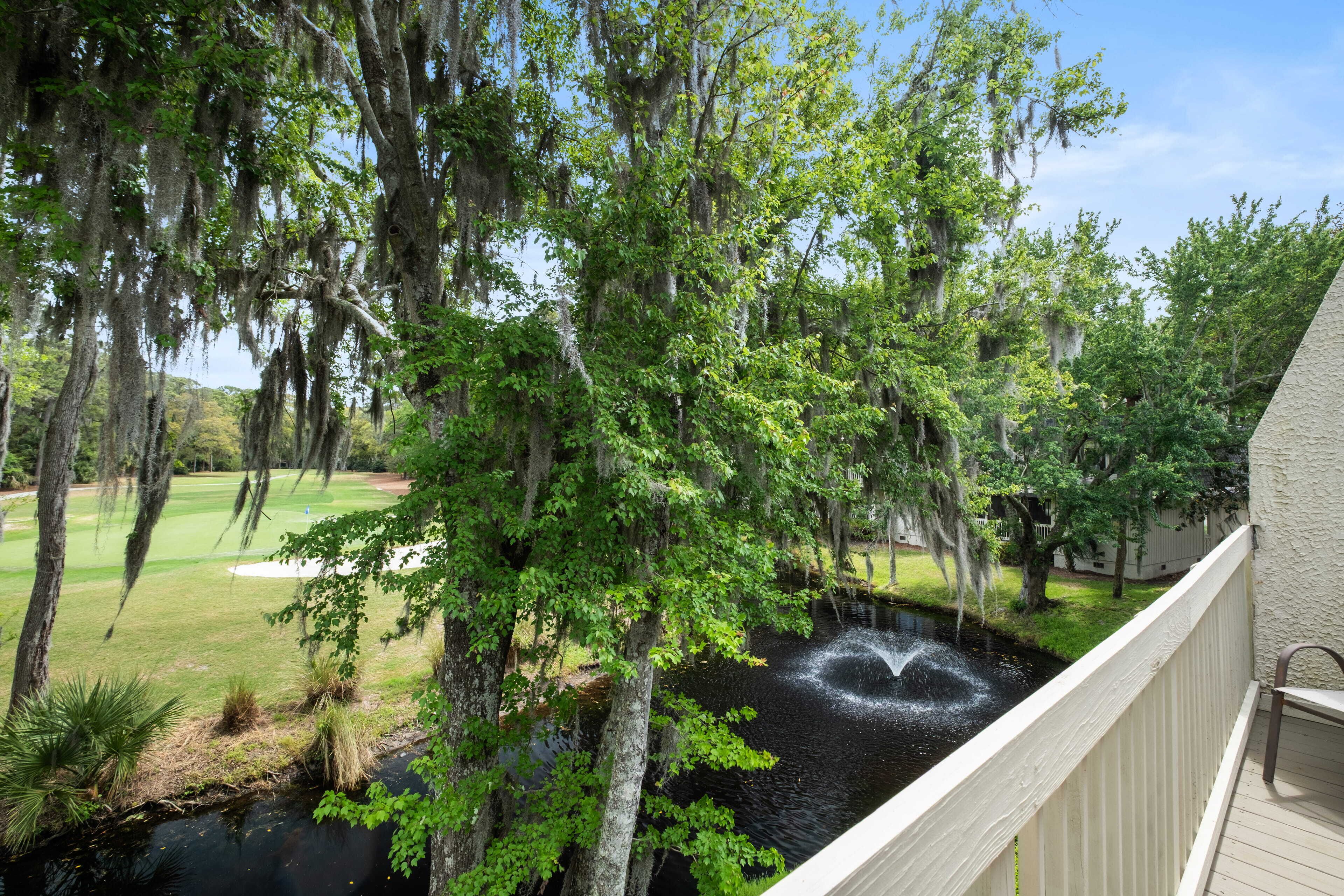A view of a golf course with a pond and trees.