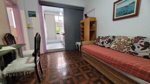 Una habitación con un sofá, un armario de madera, una silla y una mesa.