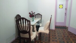 Un comedor con una mesa de vidrio, sillas de madera, un jarrón de flores y un suelo estampado.