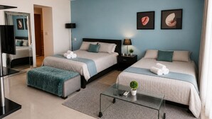 A hotel room with two beds, a TV, a small table with a plant, and artwork on the wall.
